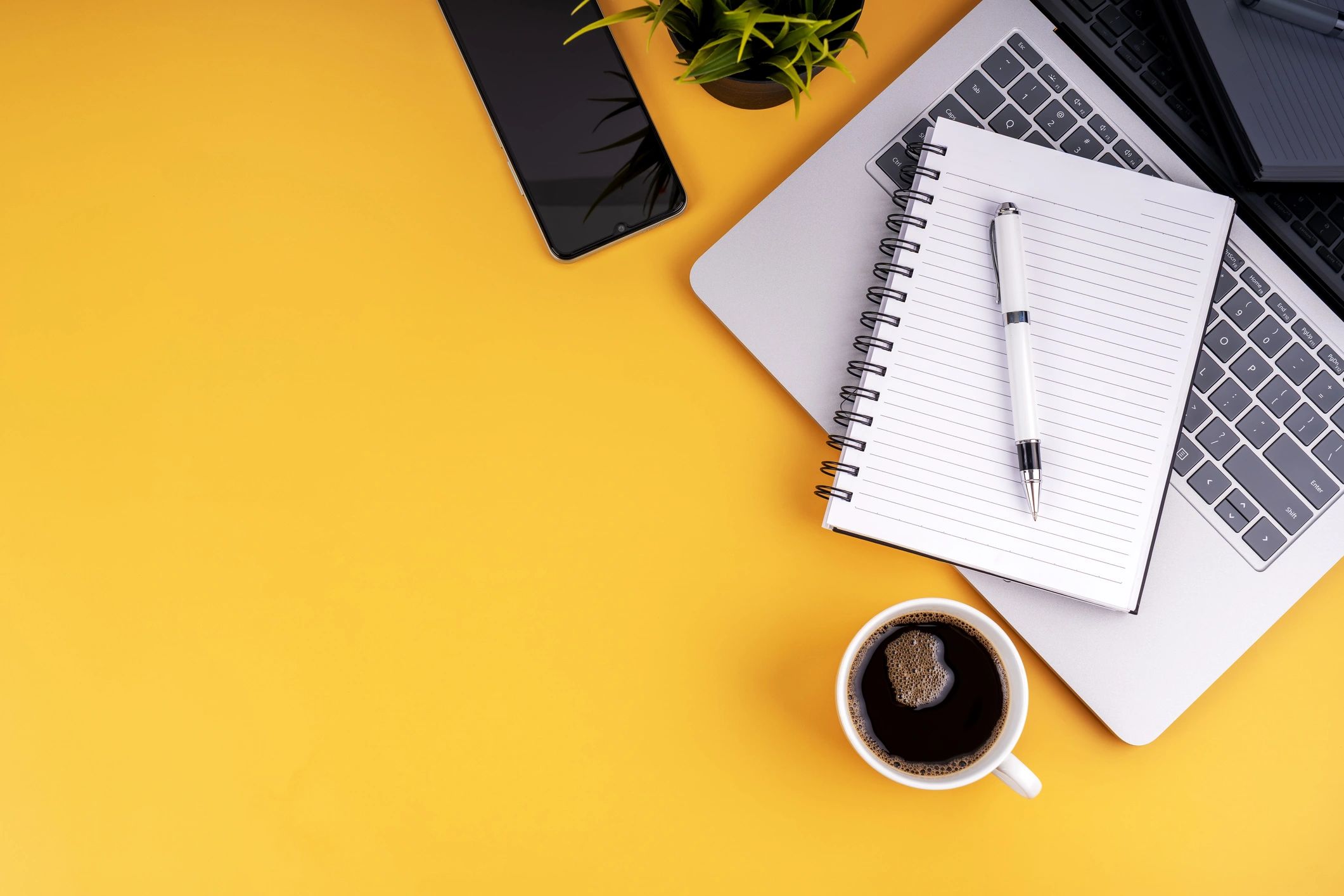 Laptop, notebook, and coffee on a workspace